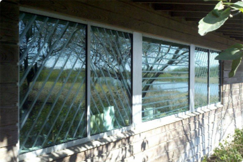 Stripes of bird tape are affixed on glass windows on a house.