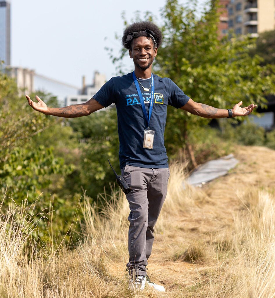 Rashid Poulson, horticultural director of Brooklyn Bridge Park, stands with his arms outstretched on one of the sound berms.
