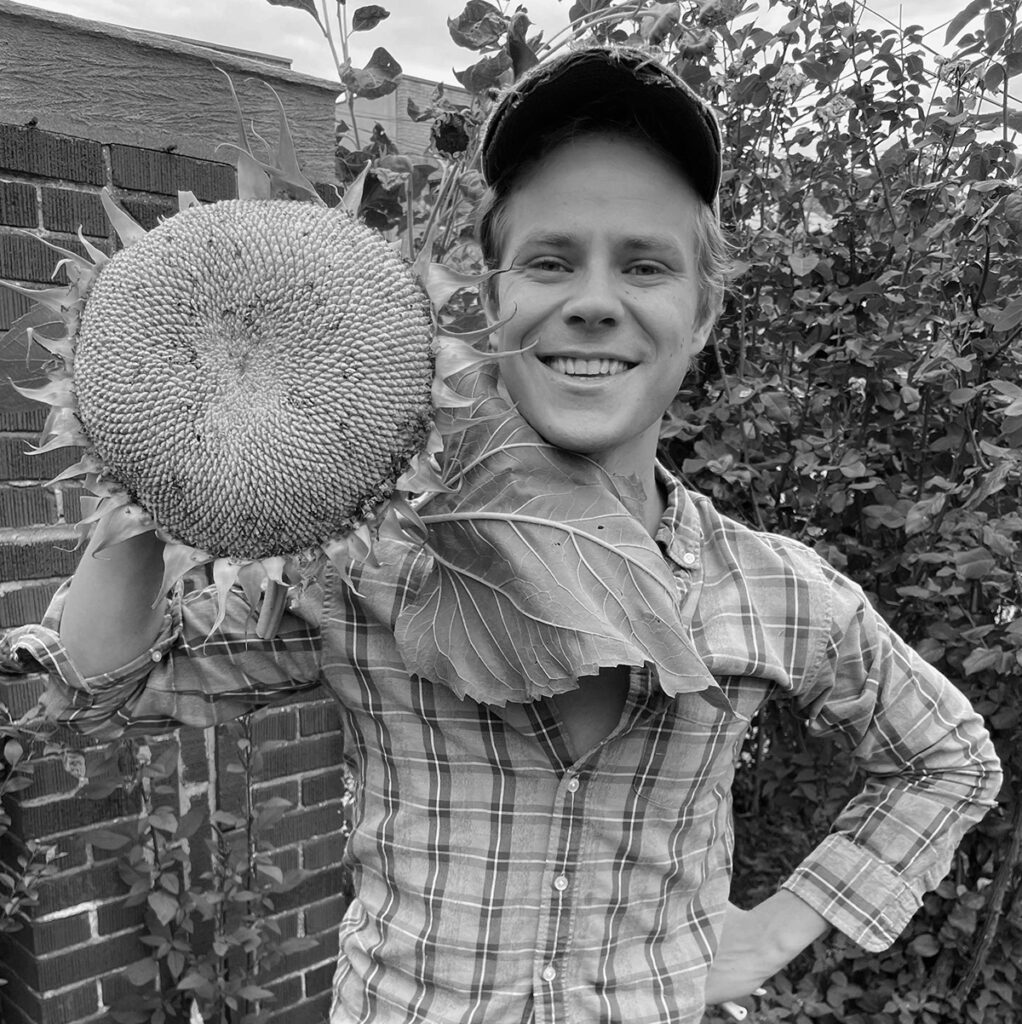 Sam Adams holding a large sunflower.